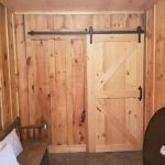 Close up of a hallway with a wood sliding barn door and a long wood bench.