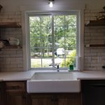 Close up of a kitchen's white farmhouse sink overlooking the home's backyard.