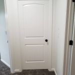 Close up of a white door in a white hallway.