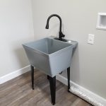 Deep laundry tub sink with a gray tub, black metal legs, and a black sink faucet.