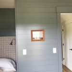 Close up of a wall with green wood wall cladding and a framed landscape wall hanging.