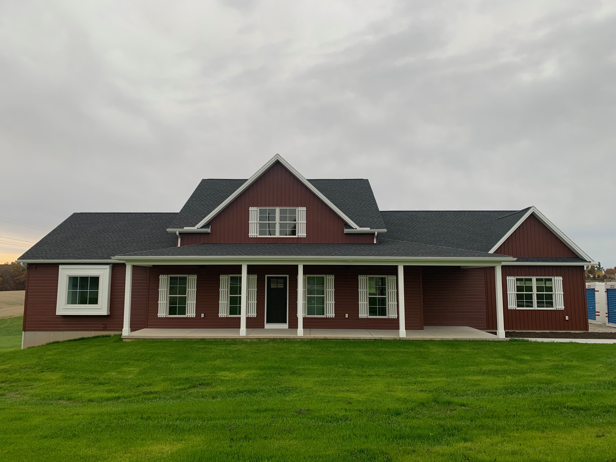 new home build with red siding, white window shutters and columns