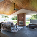 covered outdoor living space with couches, fireplace, hot tub, outdoor table, and outdoor kitchen