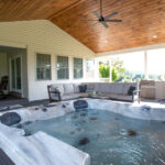 covered porch addition with a living space, outdoor kitchen, dining space, and hot tub