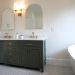new bathroom with green counters, two sinks, and gold fixtures