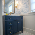 bathroom with floral wallpaper, blue sink counter, and square mirror