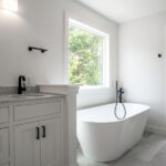 new primary bathroom with marble counters and large tub