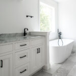 new primary bathroom with marble counters and large tub