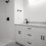 double sink with marble counters next to a shower