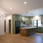 new kitchen with green cabinets and wooden island