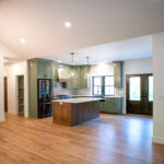 new kitchen with green cabients, white counters, and wooden island