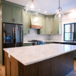 new kitchen with black appliances, green cabinets, tile backsplash, and wooden island