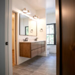 new bathroom with two sinks, wooden counters, rectangular mirror, and sconces
