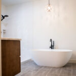 new bathroom with tub and chandelier