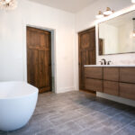 new bathroom with two sinks, wooden counters, tub, and rectangular mirror