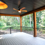 back deck of a new home with wooden beams, ceiling fan, and black railing