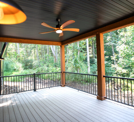 back deck of a new home with wooden beams, ceiling fan, and black railing