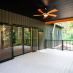 back deck of a new home with double glass doors, ceiling fan, and black railing
