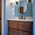 new bathroom with blue walls, wooden counter, sink, and mirror