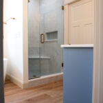 bathroom in new home with blue cabinets and walk-in shower