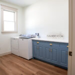 new laundry room with blue cabinets and white appliances