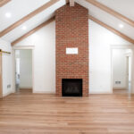 living room with hardwood floors and brick fireplace in new home