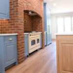 new kitchen with blue cabinets and brick arch