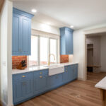 new sink in kitchen with blue cabinets and brick backsplash