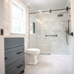 gray counter, toilet, and walk-in shower in bathroom in renovated house