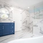bathroom renovation with marble walls and floors, blue counters, and walk-in shower