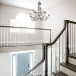top of the stairs, looking over the banister to the front door and chandelier