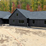 front right side view of a new ranch home with black siding