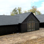 rear view of a new ranch home with black siding