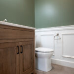 half bathroom with sink, toilet, and green and white walls