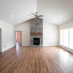 stone fireplace in an open living room with wood floors