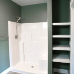 bathroom with green walls, storage, and shower