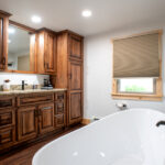 new bathroom in home addition with wooden cabinets and white tub