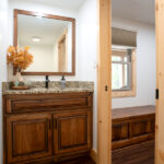 sink with wooden cabinets and square mirror