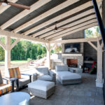 covered back porch with stone fireplace, TV, and comfortable seating