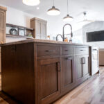 kitchen island with a sink and dark wood cabinets