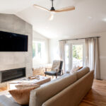 living room with a modern fireplace, TV, and cream couches