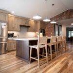 renovated kitchen with an island, stainless steel appliances, wicker bar stools, and a brick arch