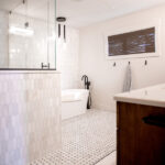renovated bathroom with double sinks, bathtub, and modern shower