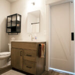 bathroom with sink, toilet, over the toilet storage, and rectangle mirror