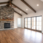 living room with stone fireplace, hardwood floors, and large doors to the outside