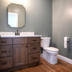 powder room bathroom with toilet and sink with hardwood cabinet