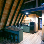 remodeled kitchen with green cabinets and bar seating