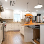 kitchen addition with white cabinets, island, tile backsplash, and kitchenaid stand mixer cabinet in island