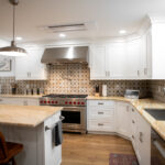 kitchen addition with white cabinets, wooden counters, tile backsplash, and island