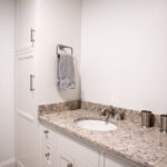 sink with white cabinets and marble countertop